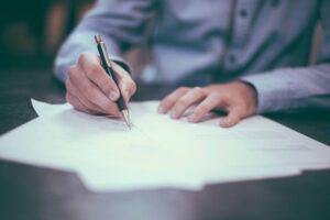 Person signing documents with a pen, symbolizing tax resolution and legal services in Dallas, Texas.